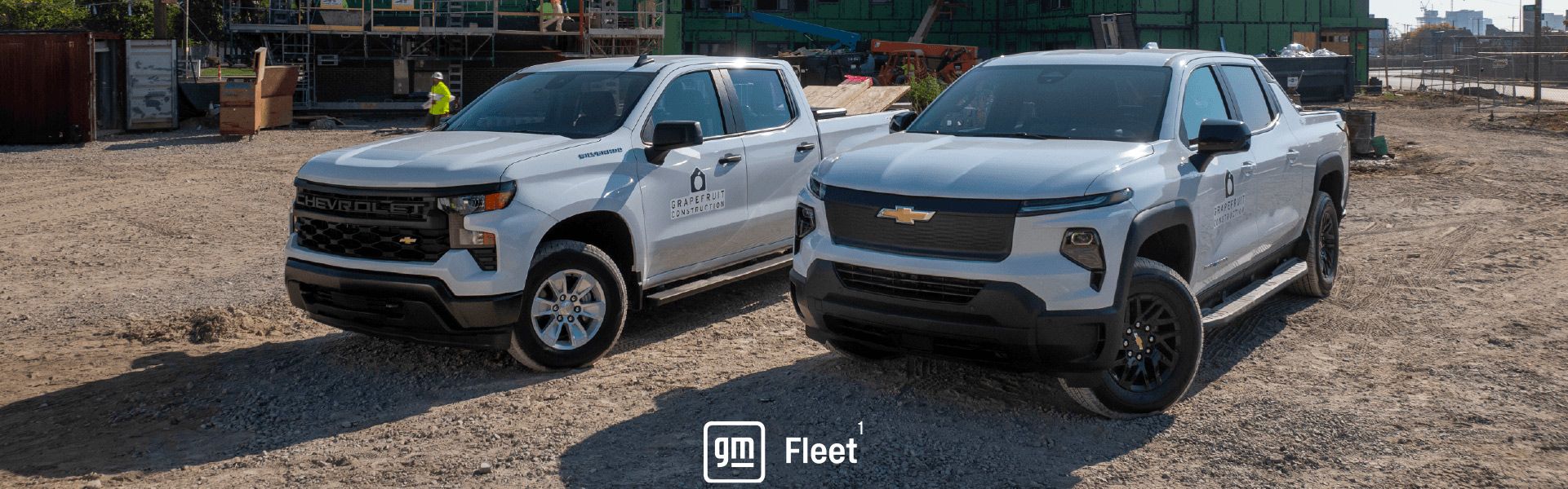 Two white Chevrolet pickup trucks parked on a dirt construction site with the GM Fleet logo at the bottom center.