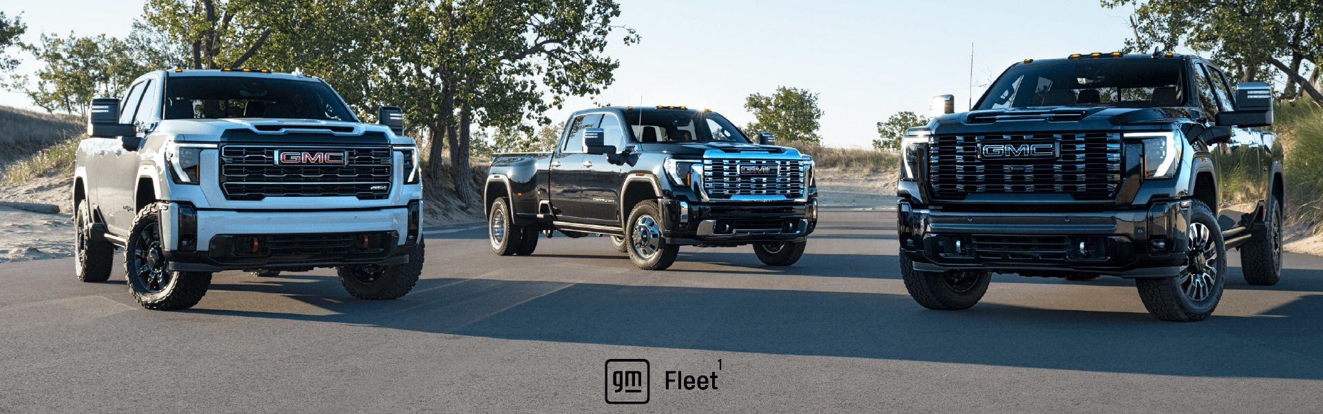 Three GMC Sierra Heavy Duty pickup trucks parked on a road. The GM Fleet logo is centered at the bottom.