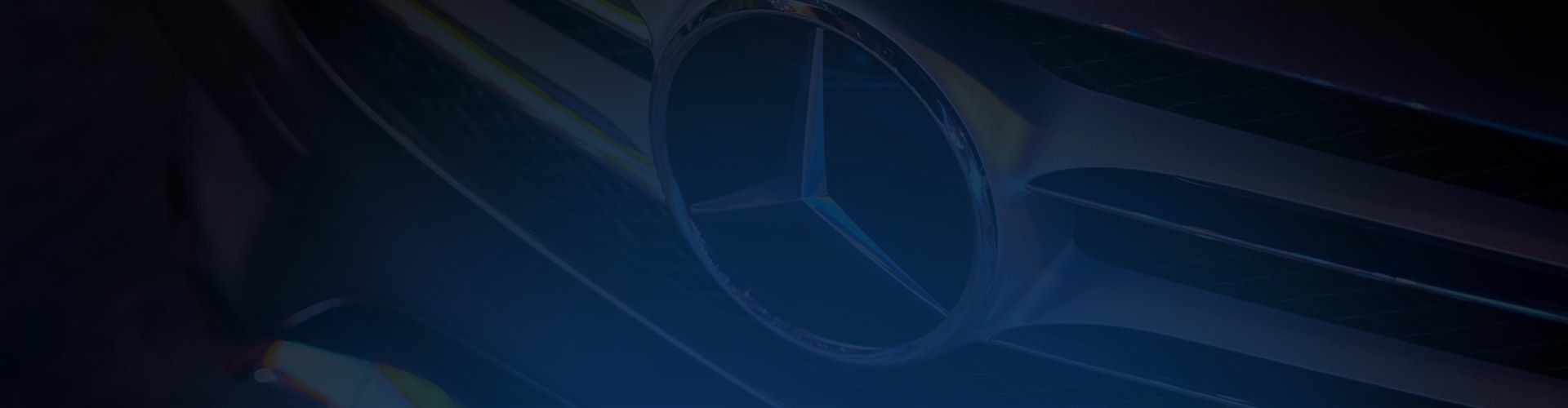 Close-up of the iconic Mercedes-Benz star emblem on a car grille with a dark blue overlay.