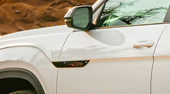 Close-up of the side panel of a white SUV, highlighting the Peak Edition badge and the side-view mirror.