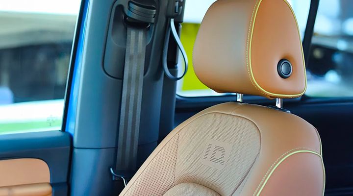 Close-up of a light brown leatherette front seat, showing a perforated ID. pattern, indicating massage or ventilation features.