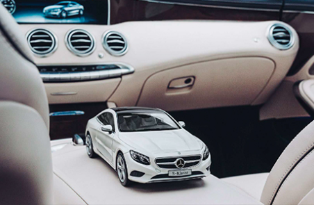 Miniature d'une Mercedes-Benz blanche posée sur le siège d'un véhicule