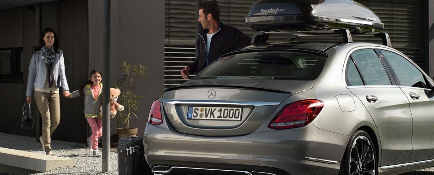 Famille chargeant une Mercedes-Benz avec un coffre de toit pour un voyage
