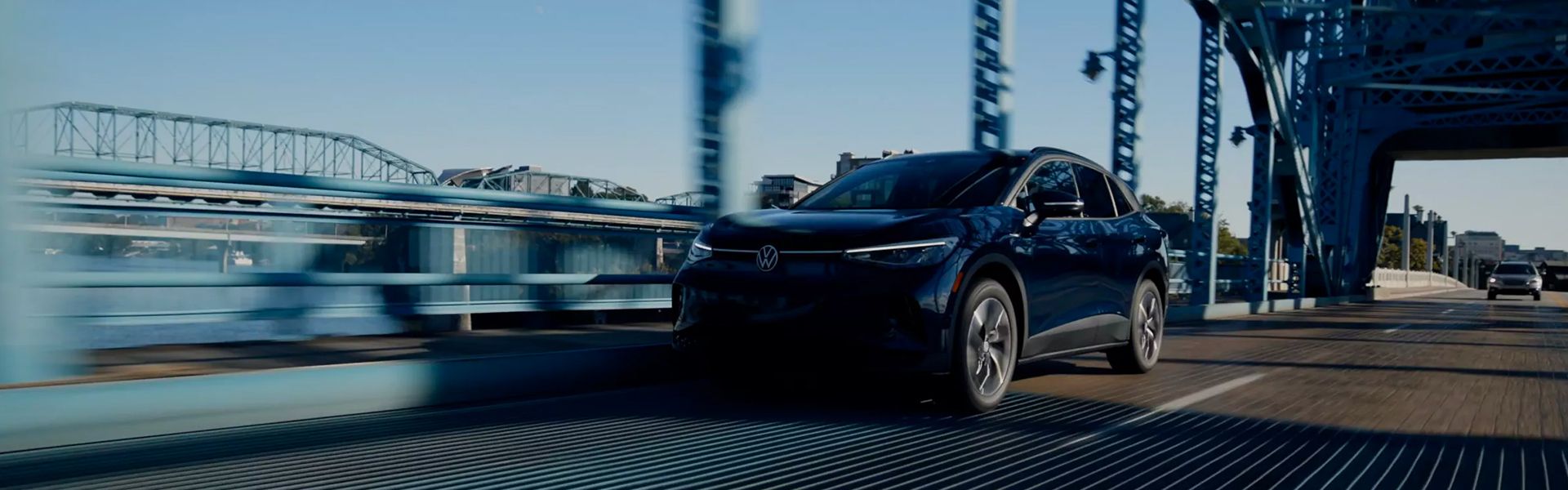 Blue Volkswagen driving across a bridge.