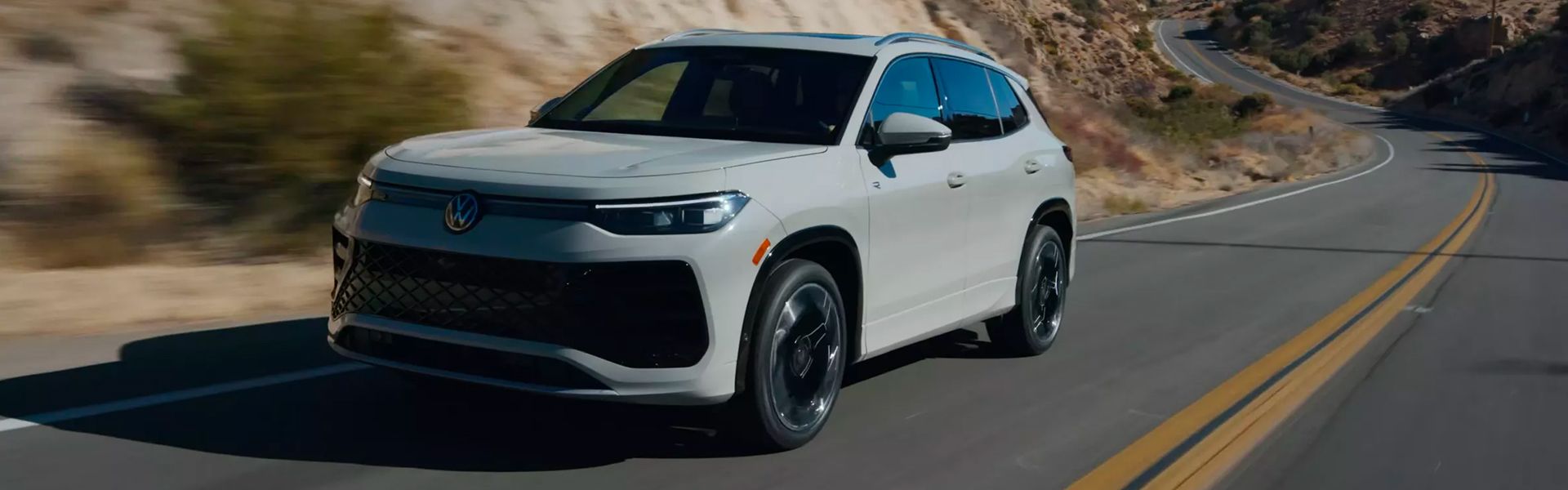White SUV driving on a winding road.