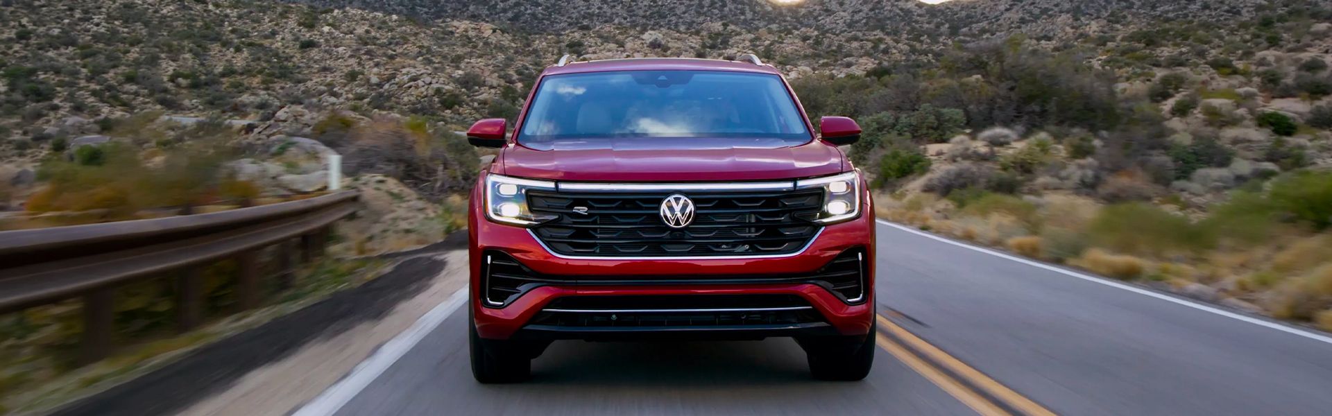 Red Volkswagen SUV driving on a mountain road.