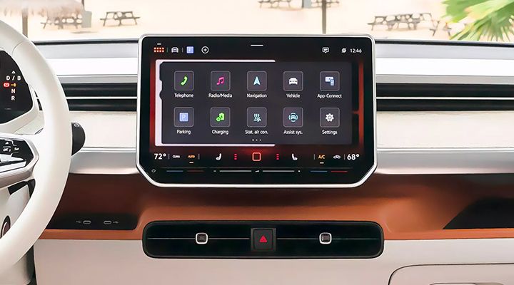 Gros plan sur l'écran tactile du système d'infodivertissement d'une voiture, affichant les icônes des applications (Navigation, Chargement, etc.).