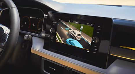 Close-up of a car's infotainment screen displaying driver assistance features (a 3D view of two cars on a road).