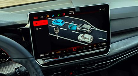 Close-up of a car's infotainment touchscreen displaying driver assistance features (Lane Assist and Side Assist), shown as car graphics on a road.