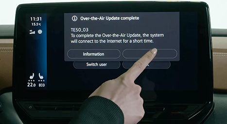 View of a car's dashboard on the highway, showing hands on the steering wheel and the digital screen displaying speed and driver assistance features.