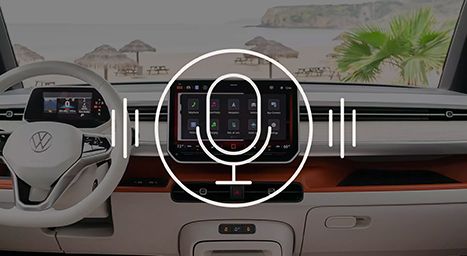 Tableau de bord intérieur d'un Volkswagen ID. Buzz avec l'écran tactile affichant l'icône du contrôle vocal devant un arrière-plan de plage.