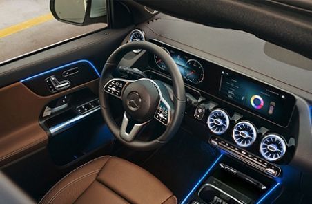 Modern dashboard of a Mercedes-Benz featuring digital screens and blue LED ambient lighting.