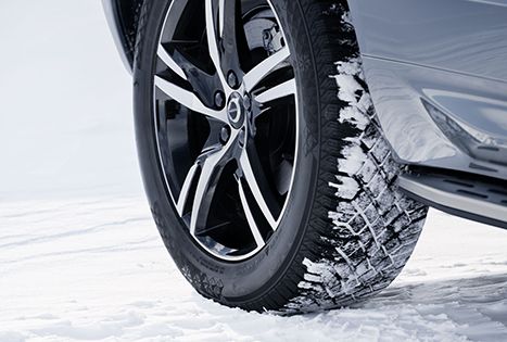 Close-up of a car's winter wheel (tire and alloy rim) driving in the snow.