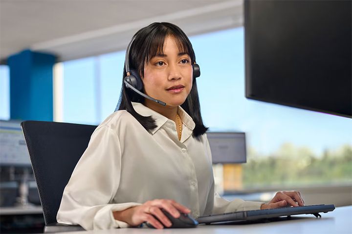 An OnStar agent or advisor wearing a headset, seated in front of a computer screen, working in a service center.