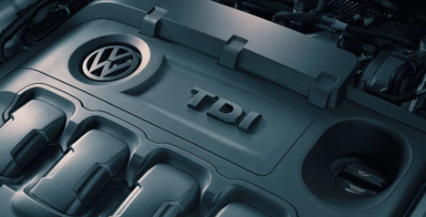 Close-up of the top of a Volkswagen engine, showing the VW and TDI logos on the engine cover.