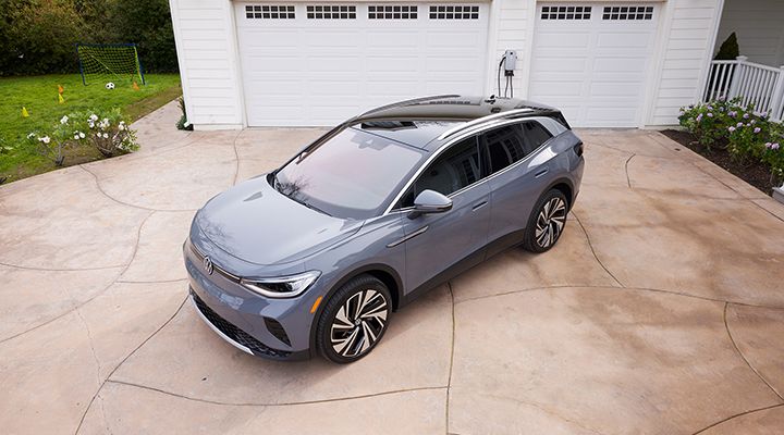 Overhead view of a gray Volkswagen ID.4 electric SUV with a black roof parked in a driveway in front of a garage.
