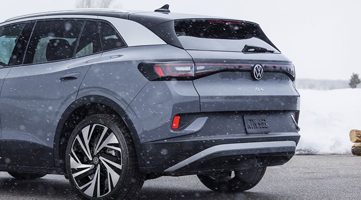 Vue arrière rapprochée d'un VUS Volkswagen ID.4 gris en train de conduire ou garé sous la neige.