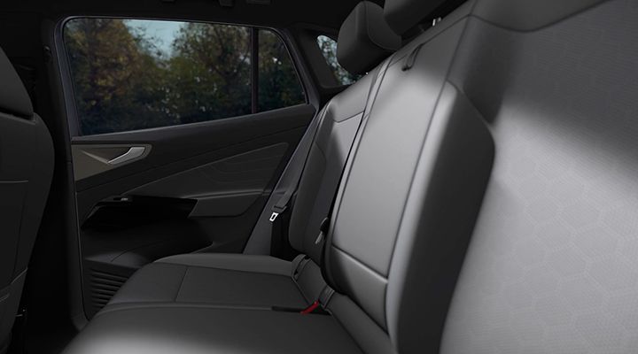 Vue rapprochée des sièges arrière d'une voiture, recouverts d'une sellerie en similicuir (leatherette) gris foncé.