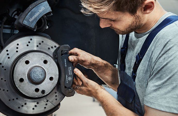 Un mécanicien installe manuellement une nouvelle plaquette sur un disque de frein Mercedes-Benz.