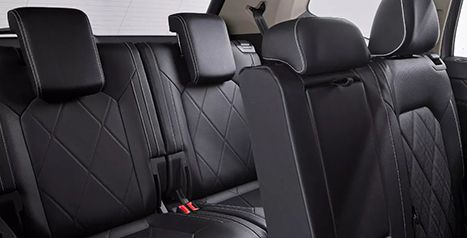 Close-up of the second-row seats of an SUV, featuring black leatherette upholstery with a diamond-stitched pattern.