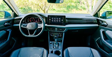 Interior view of a car, showing the steering wheel, dashboard, and central touchscreen with an automatic transmission shifter.