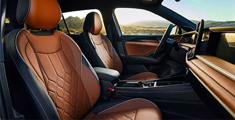 Interior view of the vehicle showing the brown and black leather sport front seats with quilted patterns, and the wood-trimmed dashboard.