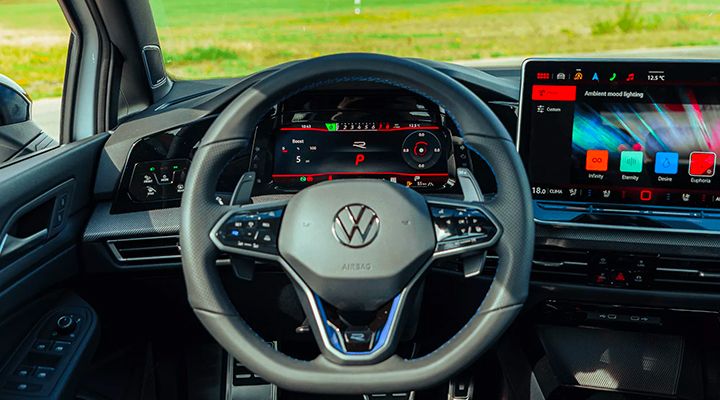 Interior view of a car, showing the sport steering wheel and the digital dashboard displaying the Sport (R) Drive Mode.