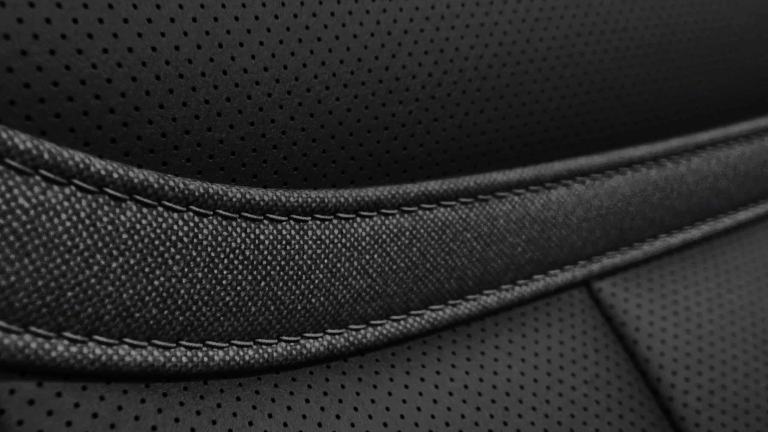 Close-up of perforated black leather texture with detailed stitching.