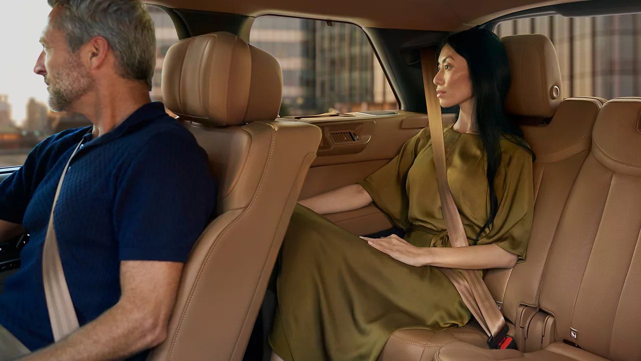 Side view of passengers seated in all three rows of tan leather seats.