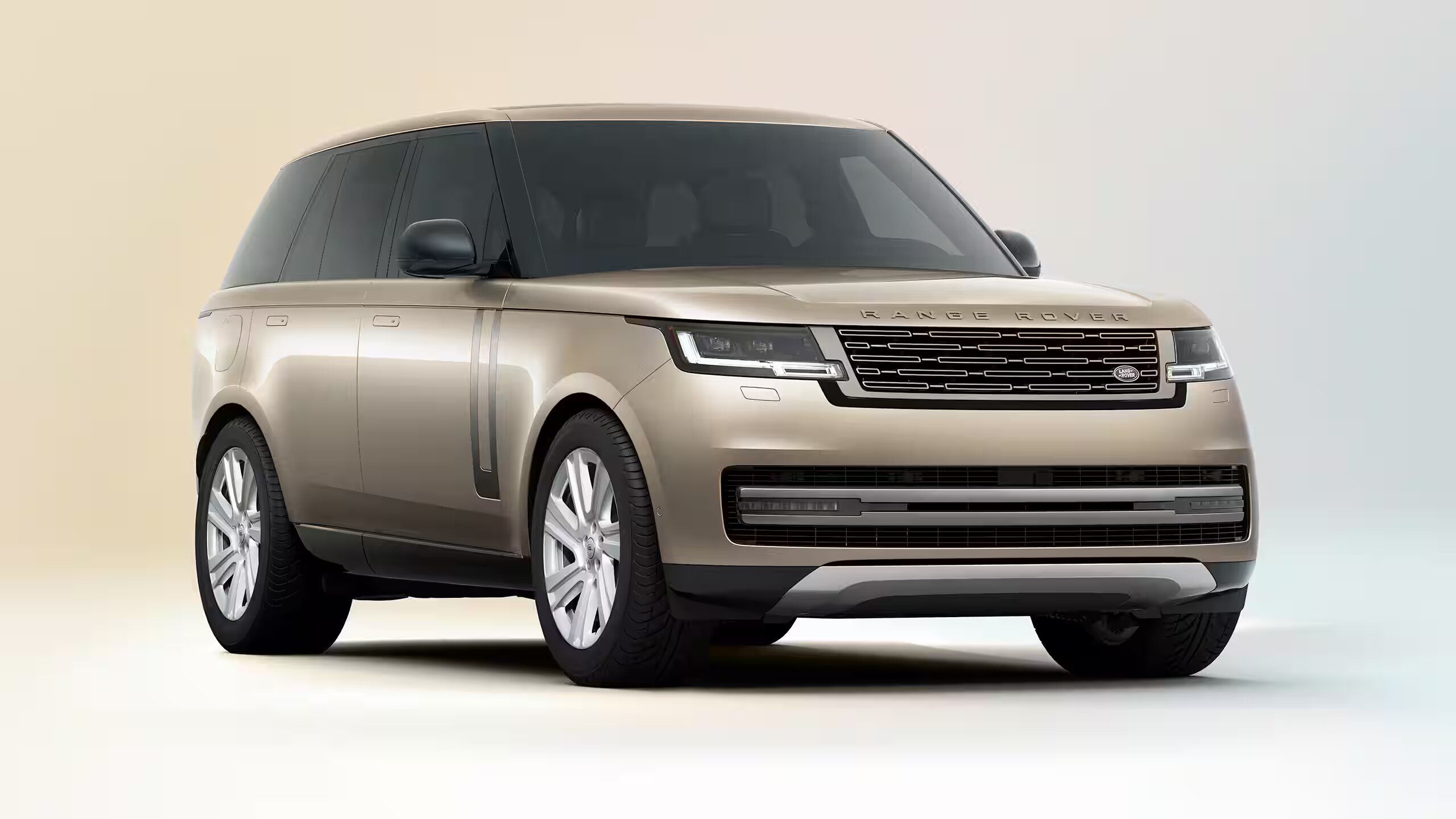 Front three-quarter view of a bronze Range Rover in a bright studio setting.