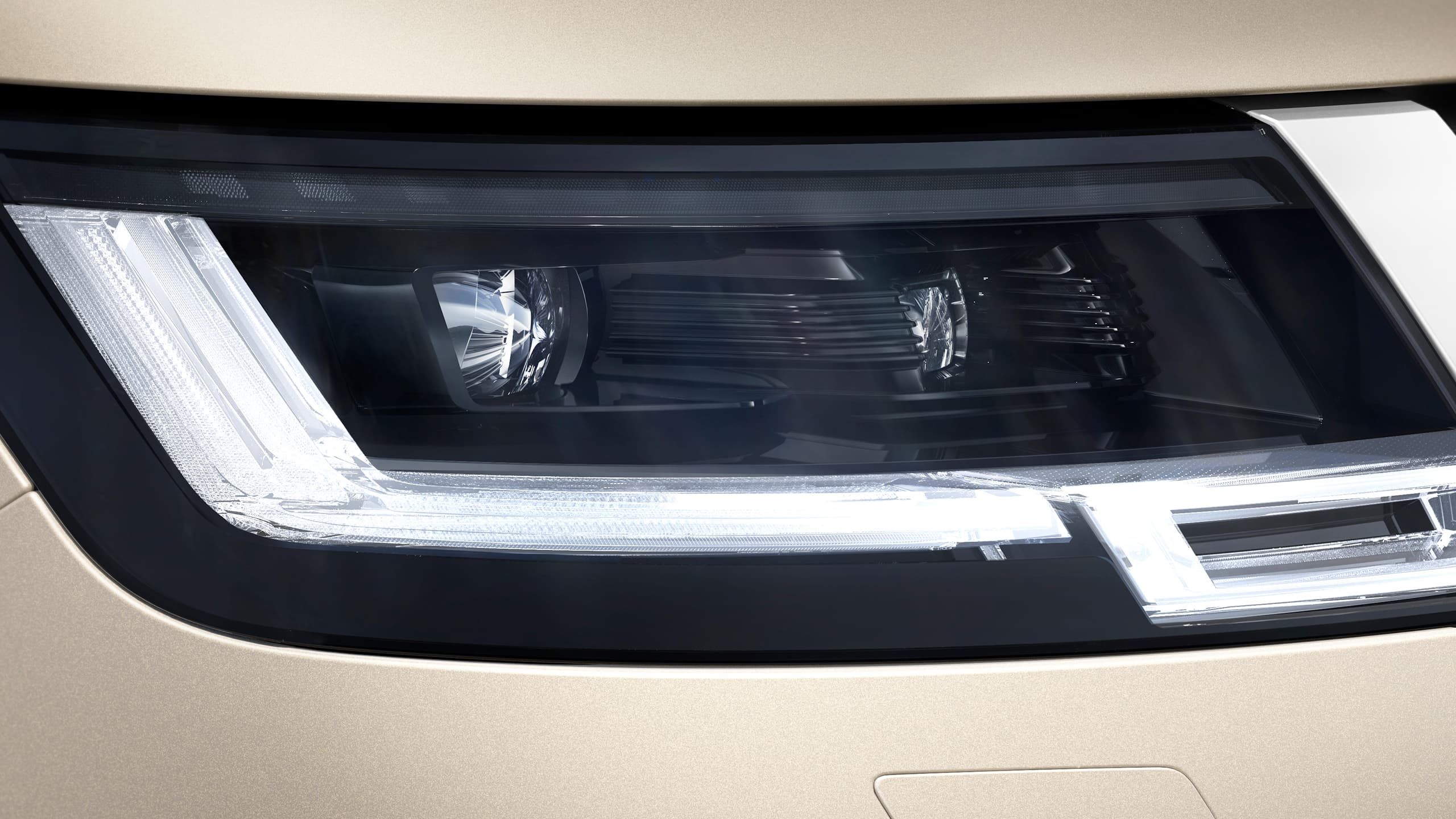 Detail of the modern LED headlight and gold-toned bodywork.