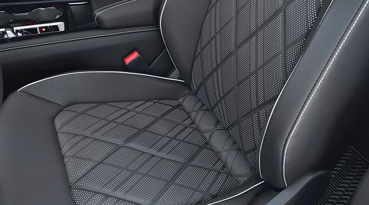 Close-up of a car's front seat, showing the quilted diamond pattern on the upholstery, indicating a massage or ventilation function.
