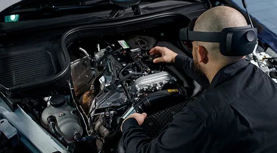 Technician wearing an augmented reality headset working on a car engine.