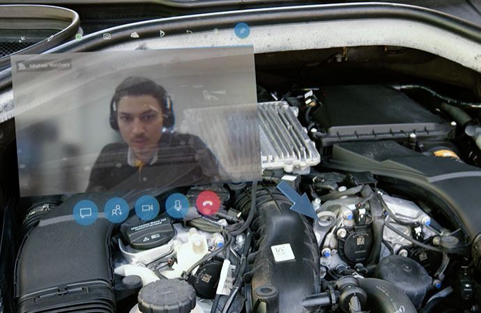 Technician wearing an augmented reality headset working on a car engine.