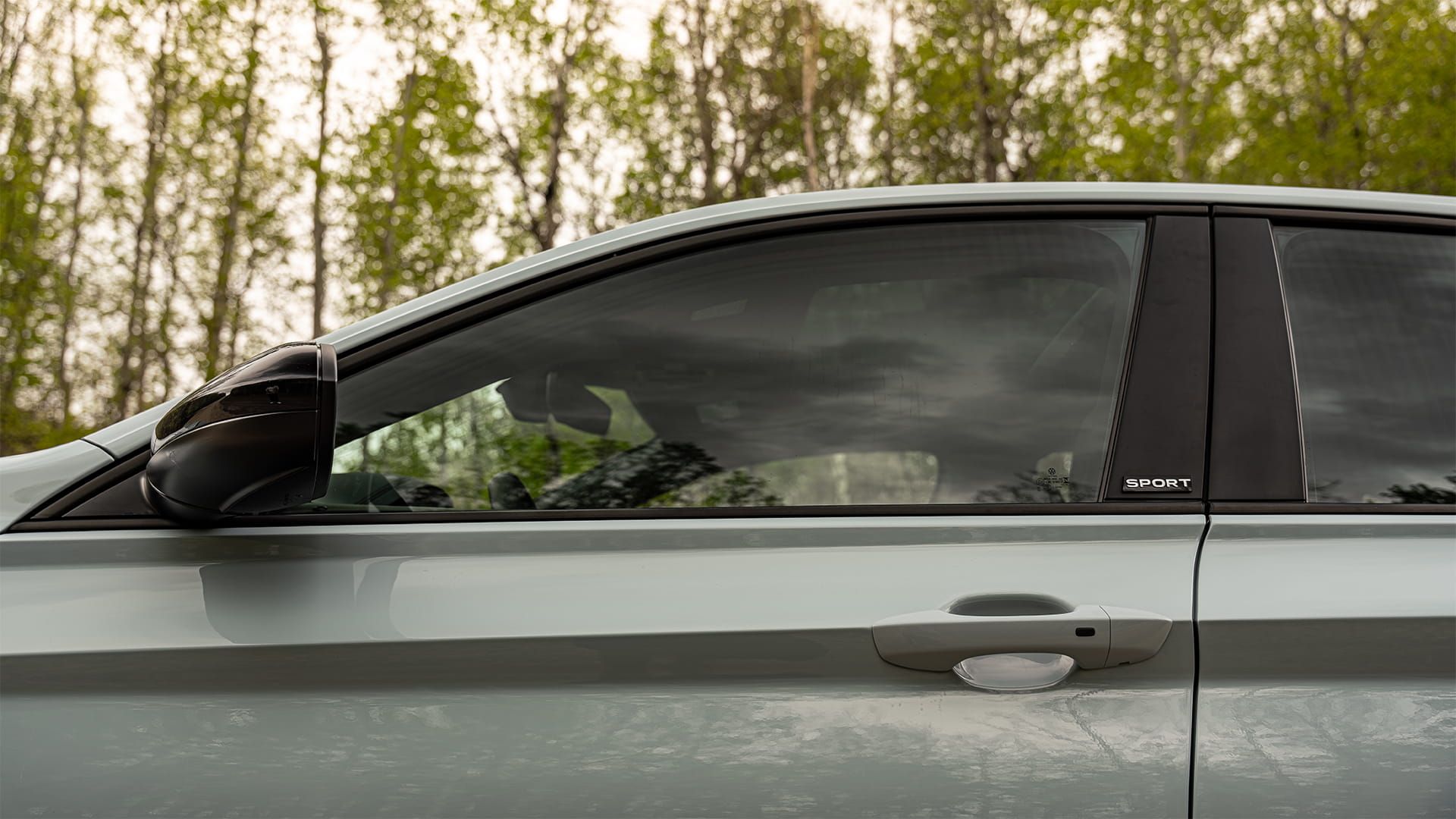 Détail de la vitre de porte sans cadre et de la garniture chromée d’une Jetta 2027 de Volkswagen de couleur argent réflexe métallisé