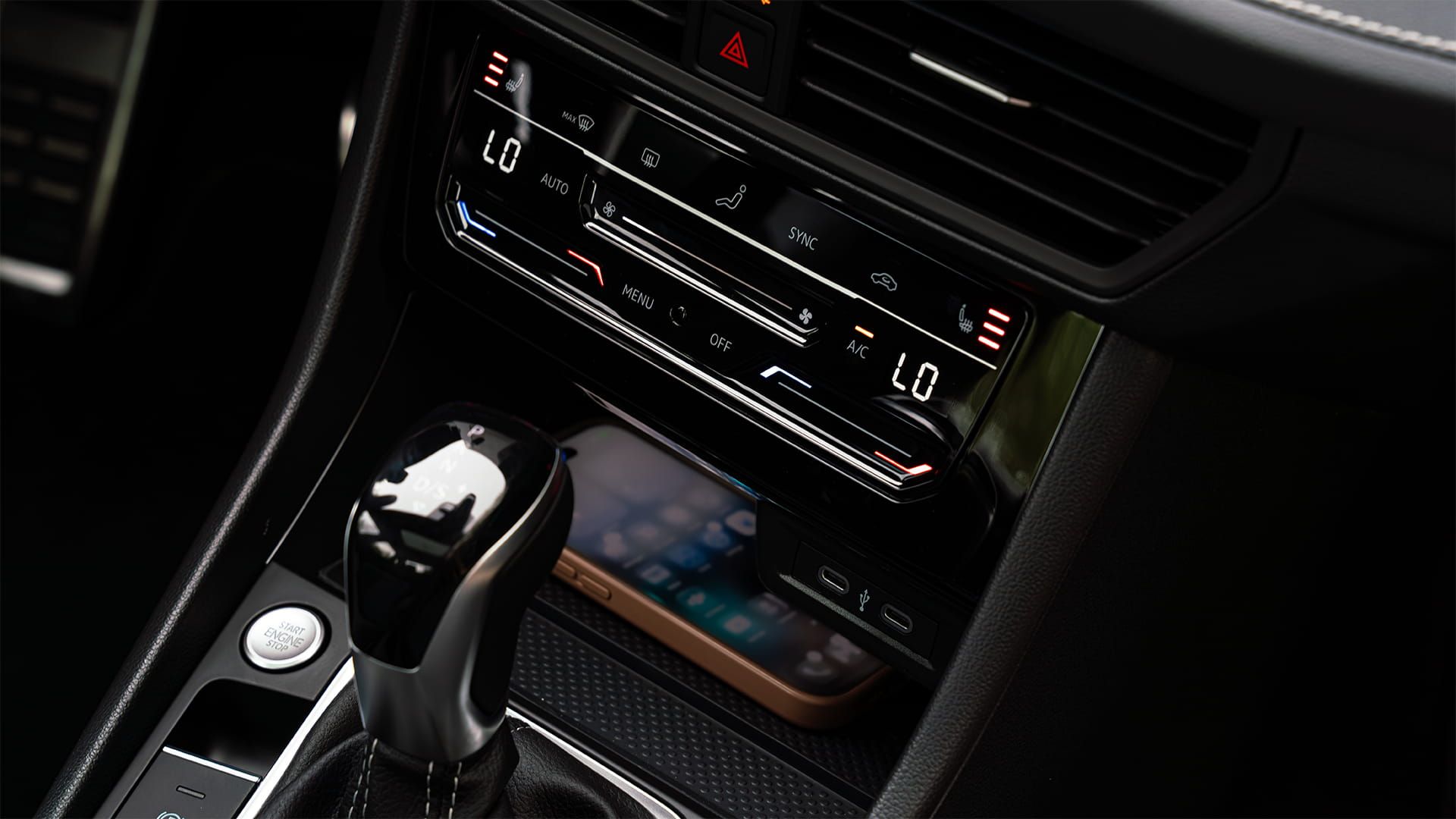 Détail intérieur du chargeur sans fil, des commandes climatiques à deux zones et du sélecteur de vitesse de la Jetta 2027 de Volkswagen