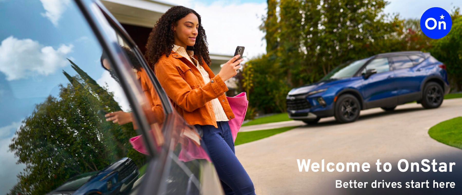 A smiling woman leans against the window of her car (a blue Chevrolet Blazer SUV) and looks at her smartphone. The text "Welcome to OnStar. Better drives start here" is displayed.