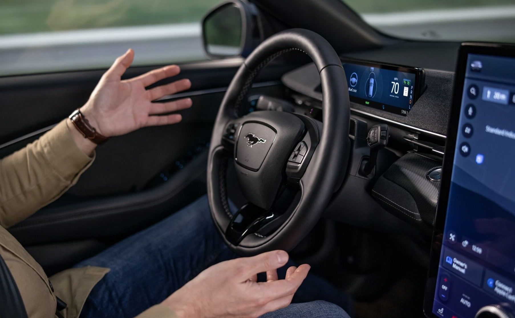 Close up of a person driving a Mustang Mach-E with their hands off the steering wheel with BlueCruise activated.