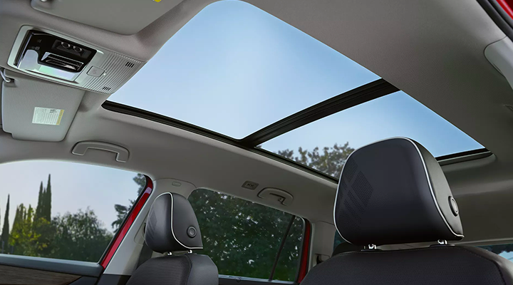 Interior view of a car showing the blue sky through the large panoramic sunroof.