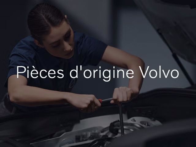 Une technicienne en chemise bleu foncé se penche sur le capot ouvert d'une voiture, utilisant une clé sur le moteur. Le texte « Pièces d'origine Volvo » est superposé sur l'image.