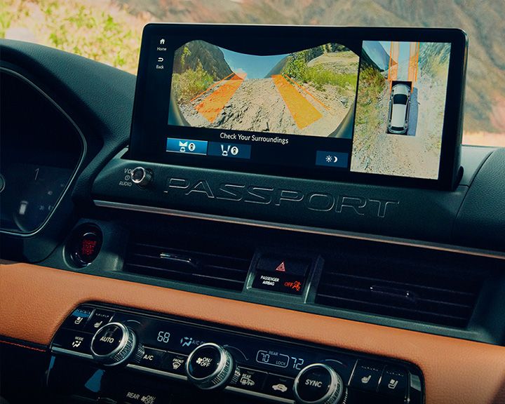 Gros plan de l'écran d'infodivertissement du tableau de bord affichant la vue de la caméra « TrailWatch » du terrain devant le véhicule, situé au-dessus des commandes de climatisation.