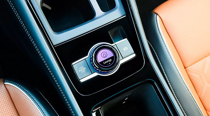 Close-up of the vehicle's center console, showing the rotary drive mode selector with "Lounge" displayed, and the "Start Engine Stop" button.