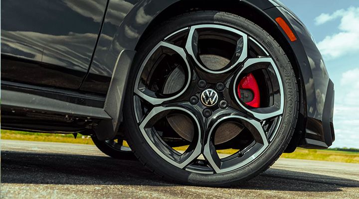 Close-up on the distinct alloy wheel of the Golf GTI, showing the red brake caliper and the VW badge on the hub.