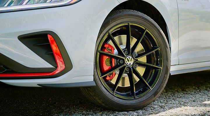 The sporty, multi-spoke black wheels of a  Jetta GLI, close-up.