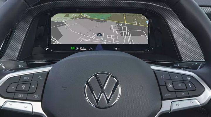 View past the steering wheel of a vehicle, showing the digital instrument cluster display with a navigation map.