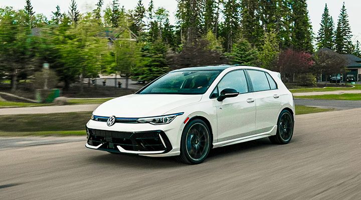 A white Volkswagen Golf R drives on a road, illustrating the 4MOTION All-Wheel Drive system.