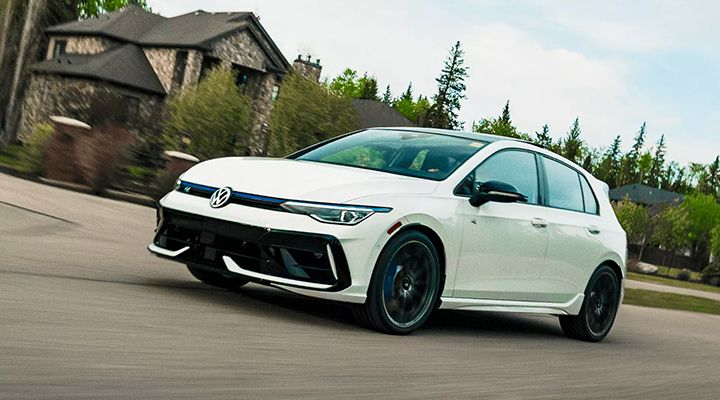 A white Volkswagen Golf R is shown taking a sharp turn in a residential area.