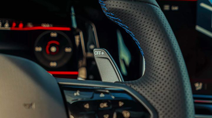 Close-up of the paddle shifter behind a car's sport steering wheel, showing the "OFF+" marking.