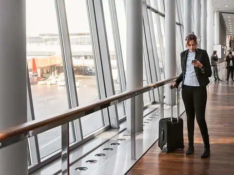 Businesswoman with luggage checking her phone in an airport terminal