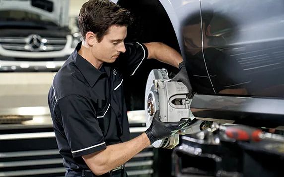 Mechanic installing or servicing a brake caliper on a car.